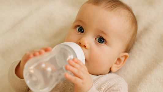 Un bébé aui boit un biberon d'eau.