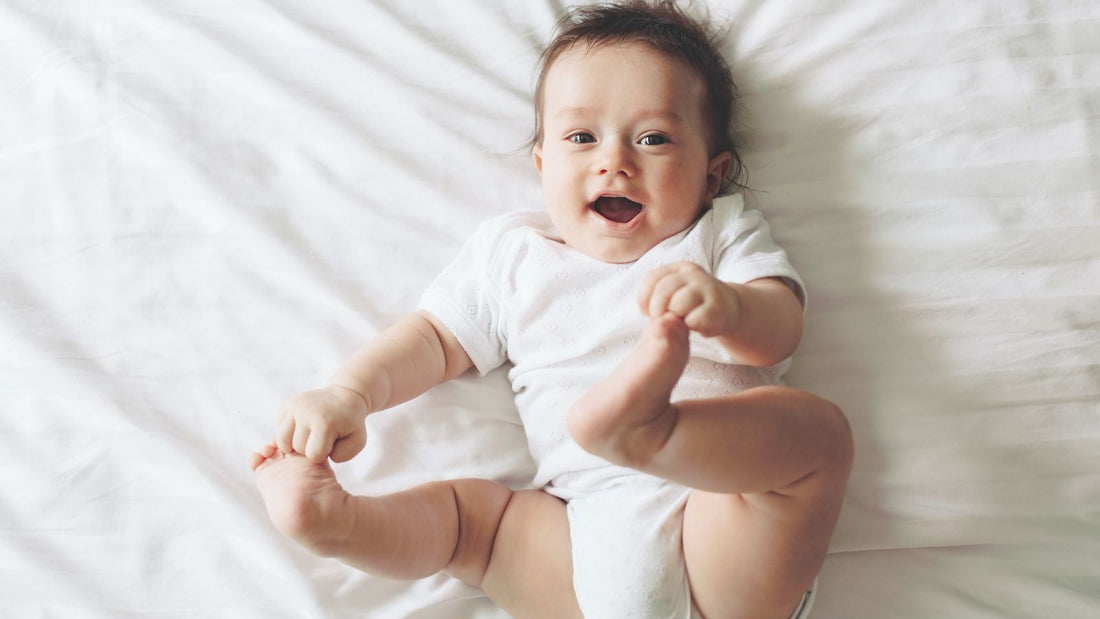 Un bébé qui sourit en tenant ses pieds dans ses mains.