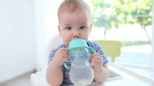 Un bébé qui boit de l'eau au biberon.