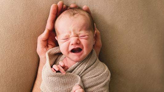 Un bébé emmailloté qui pleure.