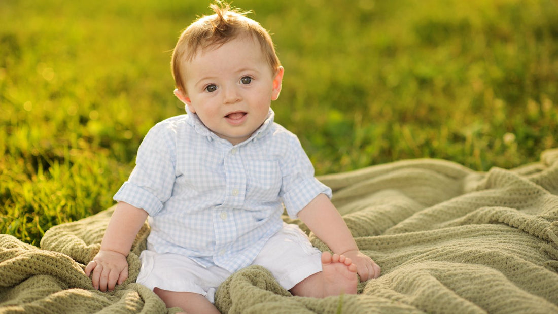 Un bébé de 5 mois sur une couverture dans un jardin