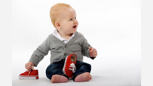 Un bébé tenant une paire de chaussure rouge à sa taille
