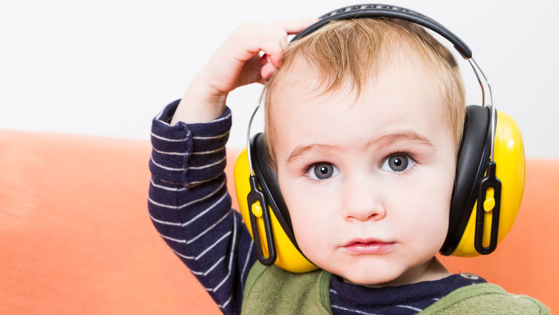 Un bébé avec un casque anti-bruit sur les oreilles.