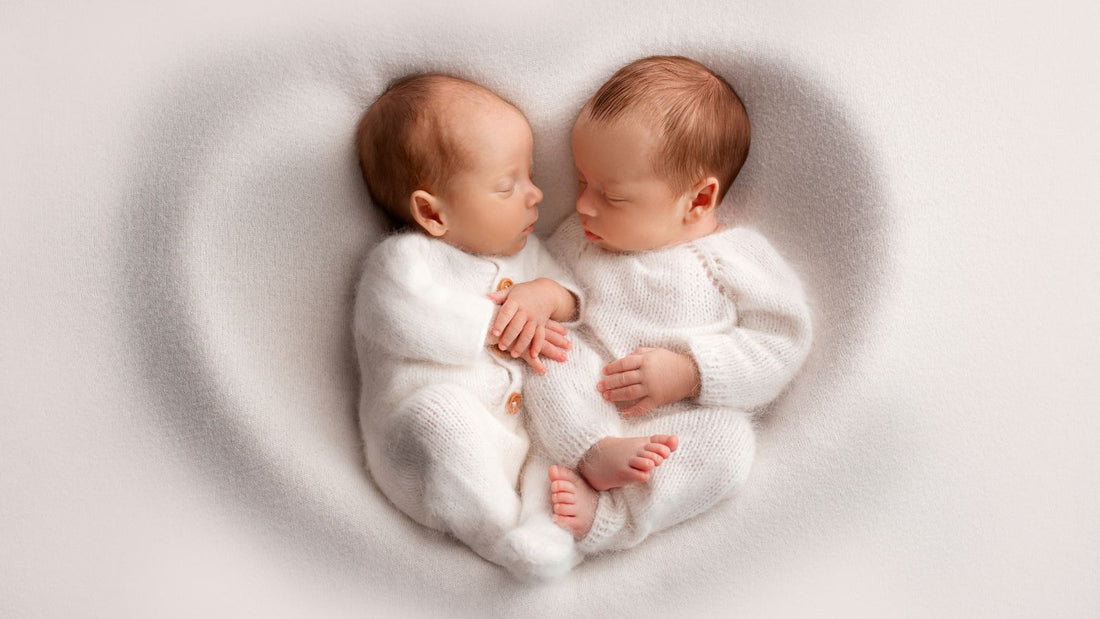 Des jumeaux posé sur un drap blanc en forme de coeur.
