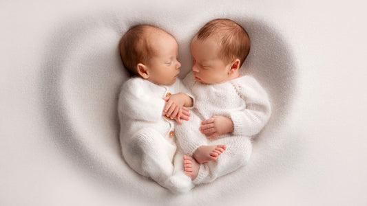 Des jumeaux posé sur un drap blanc en forme de coeur.