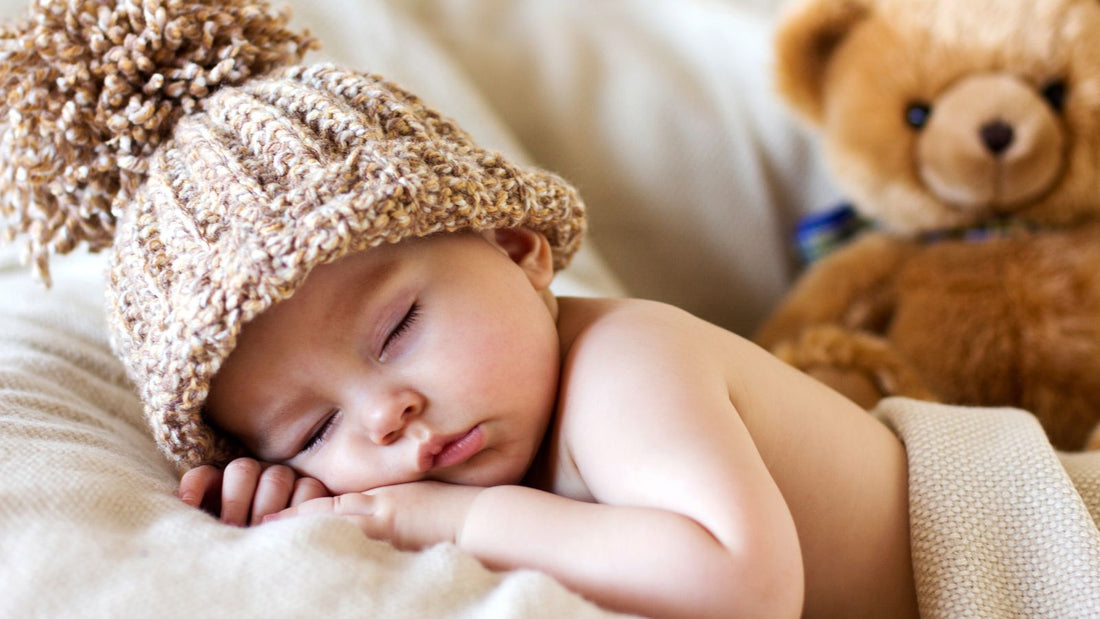 Un bébé dormant tranquillement avec son bonnet et son doudou dans le fond