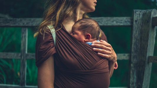 Une mama qui porte son nouveau-né en écharpe de portage.