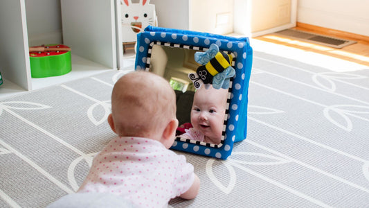 Un bébé qui se regarde dans un miroir.