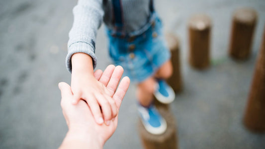 un enfant en train de jouer, posant sa main dans la paume de son parent