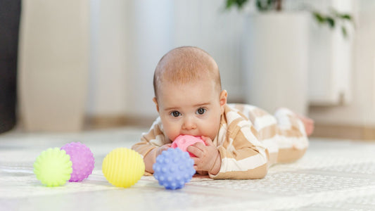 Un bébé allongé qui mâchouille une balle de préhension