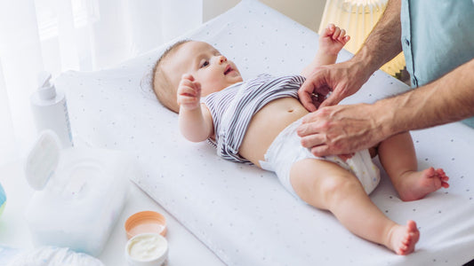 Un papa qui change la couche de son bébé.