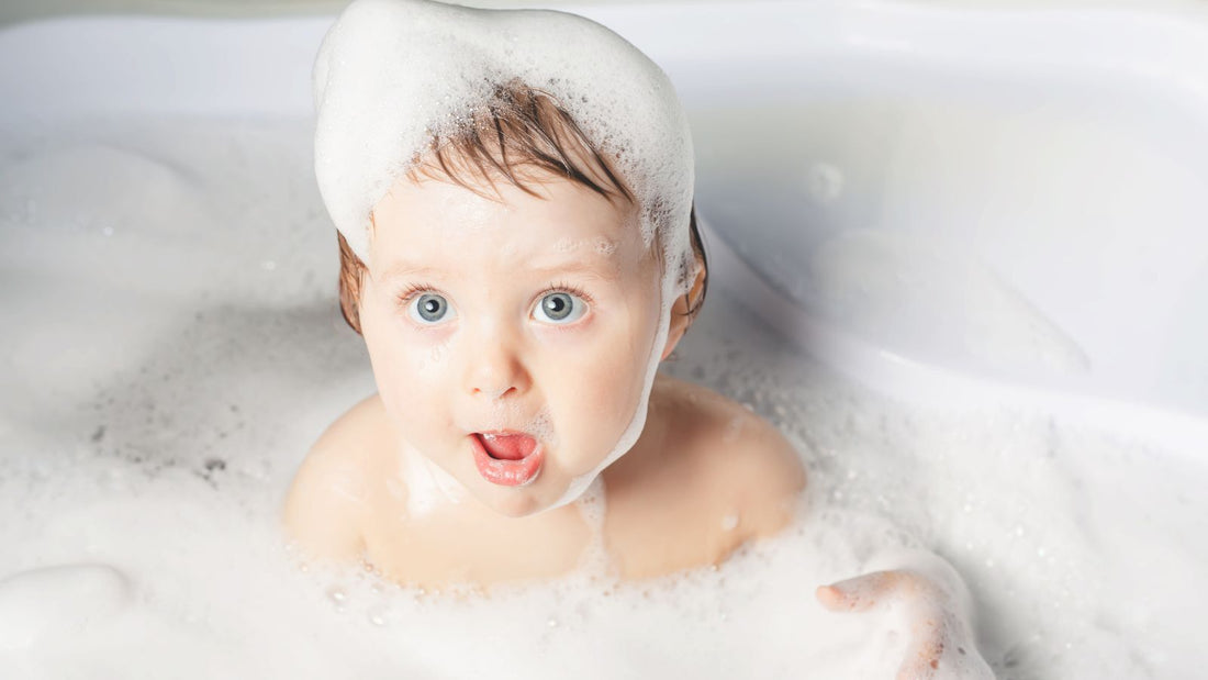 un bébé dans son bain avec de la mousse sur les cheveux