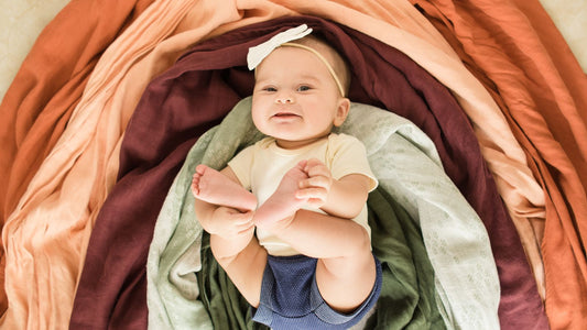 Un bébé sous des draps formant un arc-en-ciel