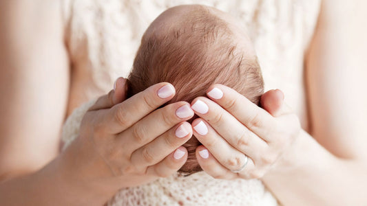 Gros plan sur la tête de bébé tenu dans les mains de sa maman